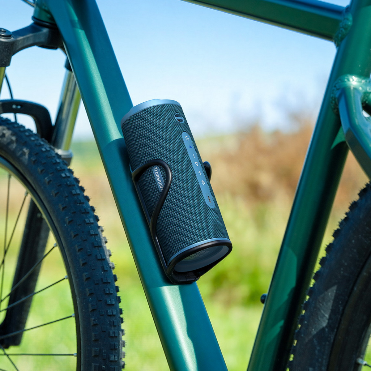 Ein zylindrischer Bluetooth-Lautsprecher ist in der Halterung eines grünen Fahrradrahmens befestigt.
