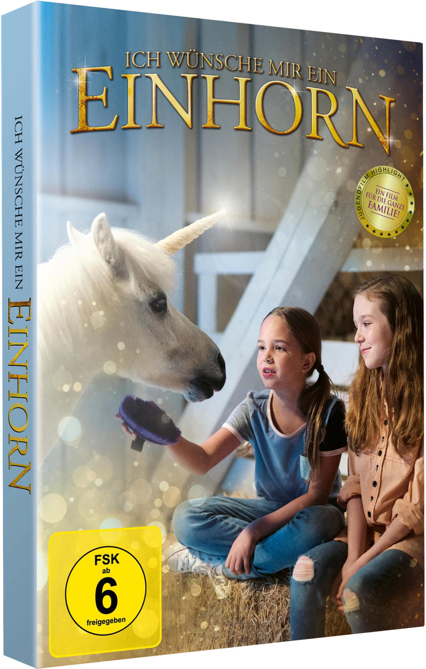 Zwei Mädchen sitzen auf Heu in einem Stall und streicheln ein weißes Einhorn.