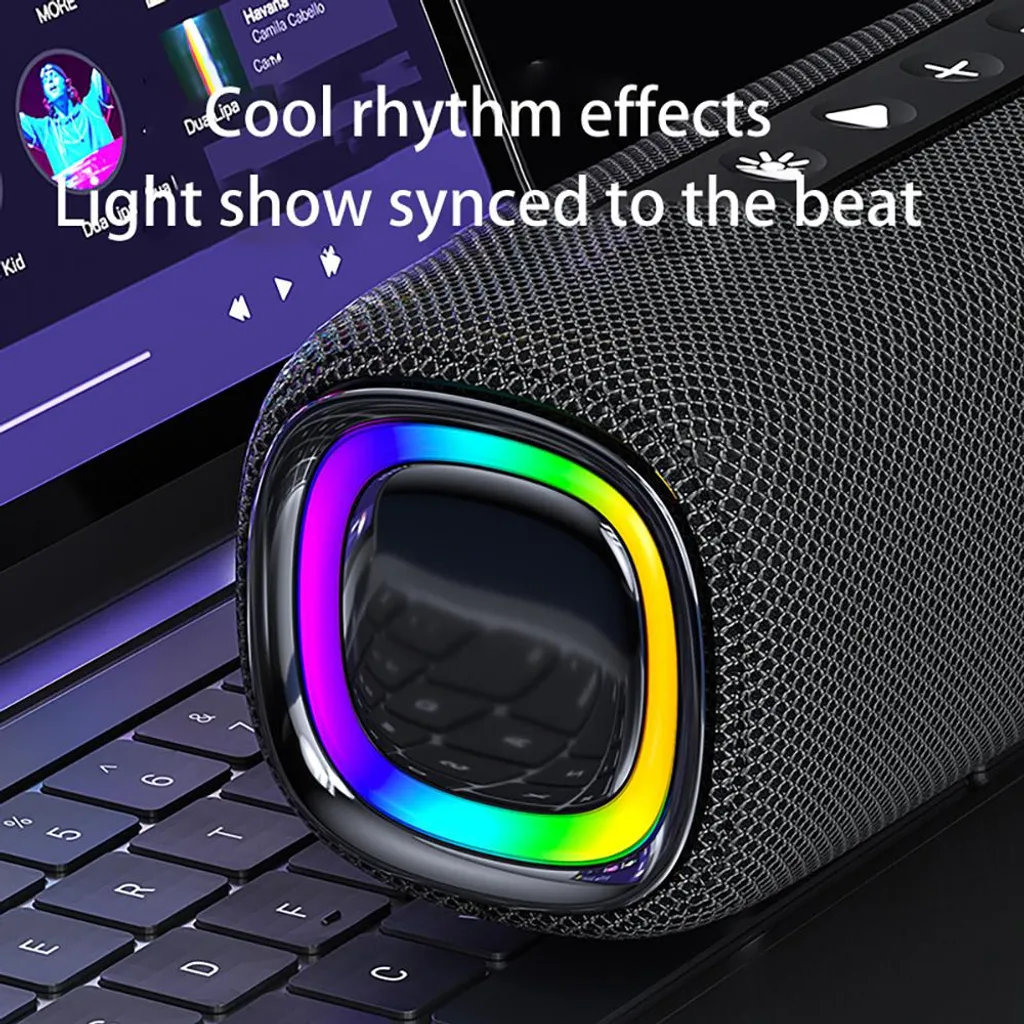 Ein zylinderförmiger, schwarzer Bluetooth-Lautsprecher mit buntem LED-Lichtring liegt auf einer Computertastatur.
