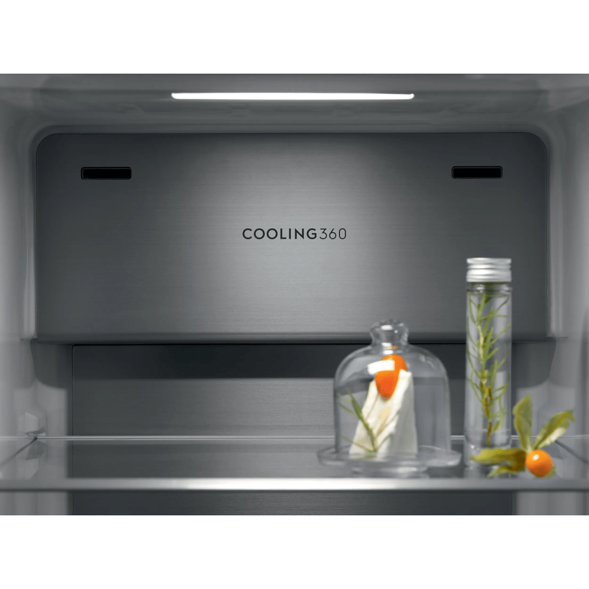 Interior de un refrigerador con panel Cooling 360, estante iluminado, queso bajo campana y botella con hierbas.