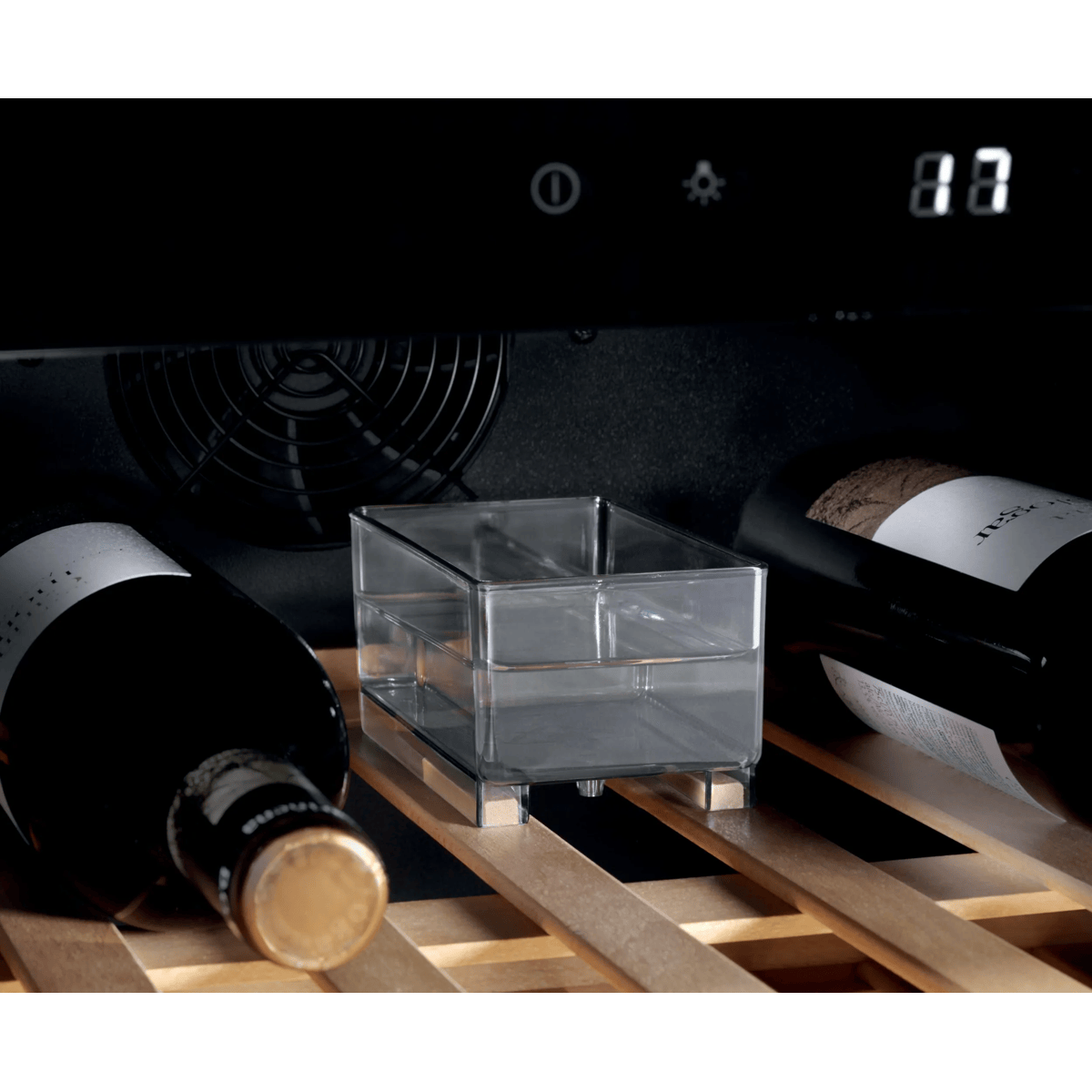 Una vinoteca con estantes de madera, dos botellas de vino, un recipiente de agua en el centro y una pantalla digital arriba.