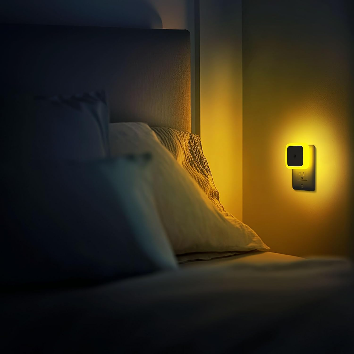 Ein warmes gelbes Nachtlicht leuchtet sanft an einer Schlafzimmerwand neben einem Bett mit Kissen.