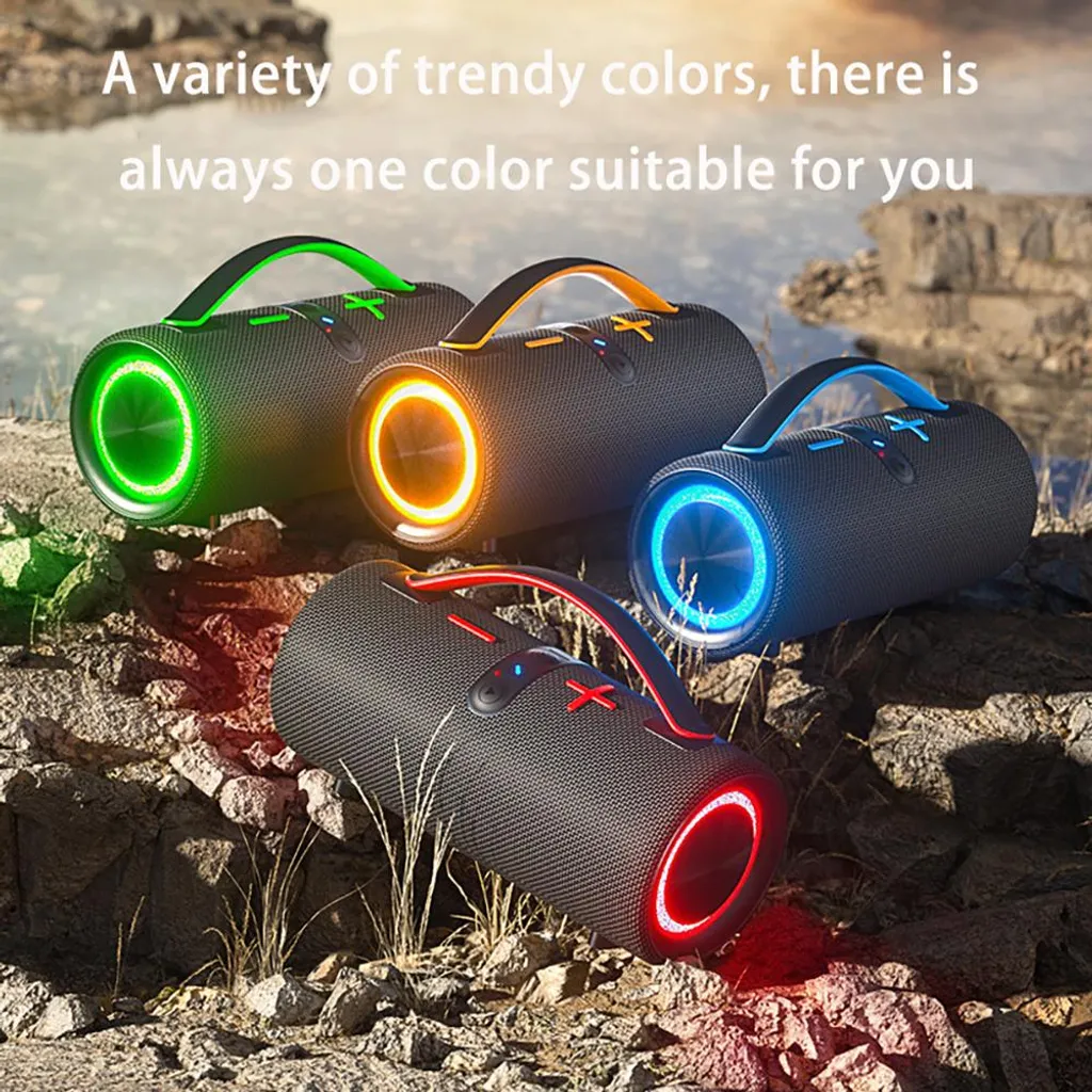 Vier zylindrische Bluetooth-Lautsprecher mit leuchtenden Ringen in Grün, Gelb, Blau und Rot auf felsigem Untergrund.