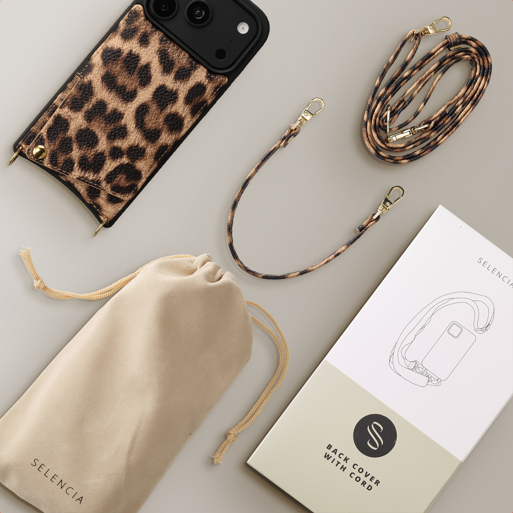 Handyhülle mit Leopardenmuster, zwei Kordeln, Samtbeutel und Verpackung auf grauem Hintergrund.
