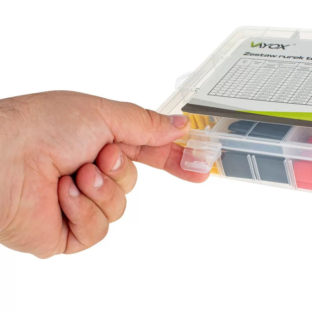 Eine Hand öffnet eine transparente Aufbewahrungsbox mit farbigen Kleinteilen.