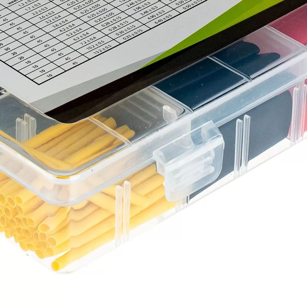 Transparente Plastikbox mit gelben und dunklen Schrumpfschläuchen, ein Datenblatt liegt auf dem Deckel.