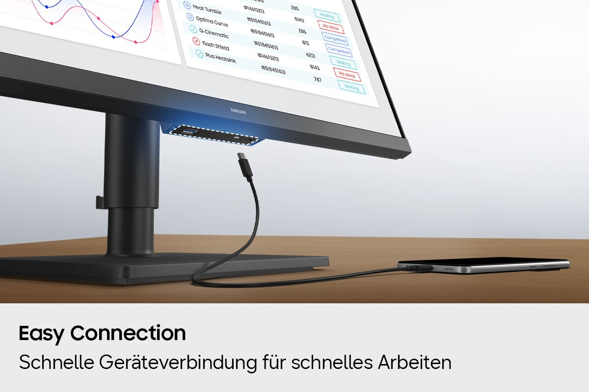 Ein USB-C-Kabel verbindet ein Smartphone mit einem Monitoranschluss auf einem Holzschreibtisch.