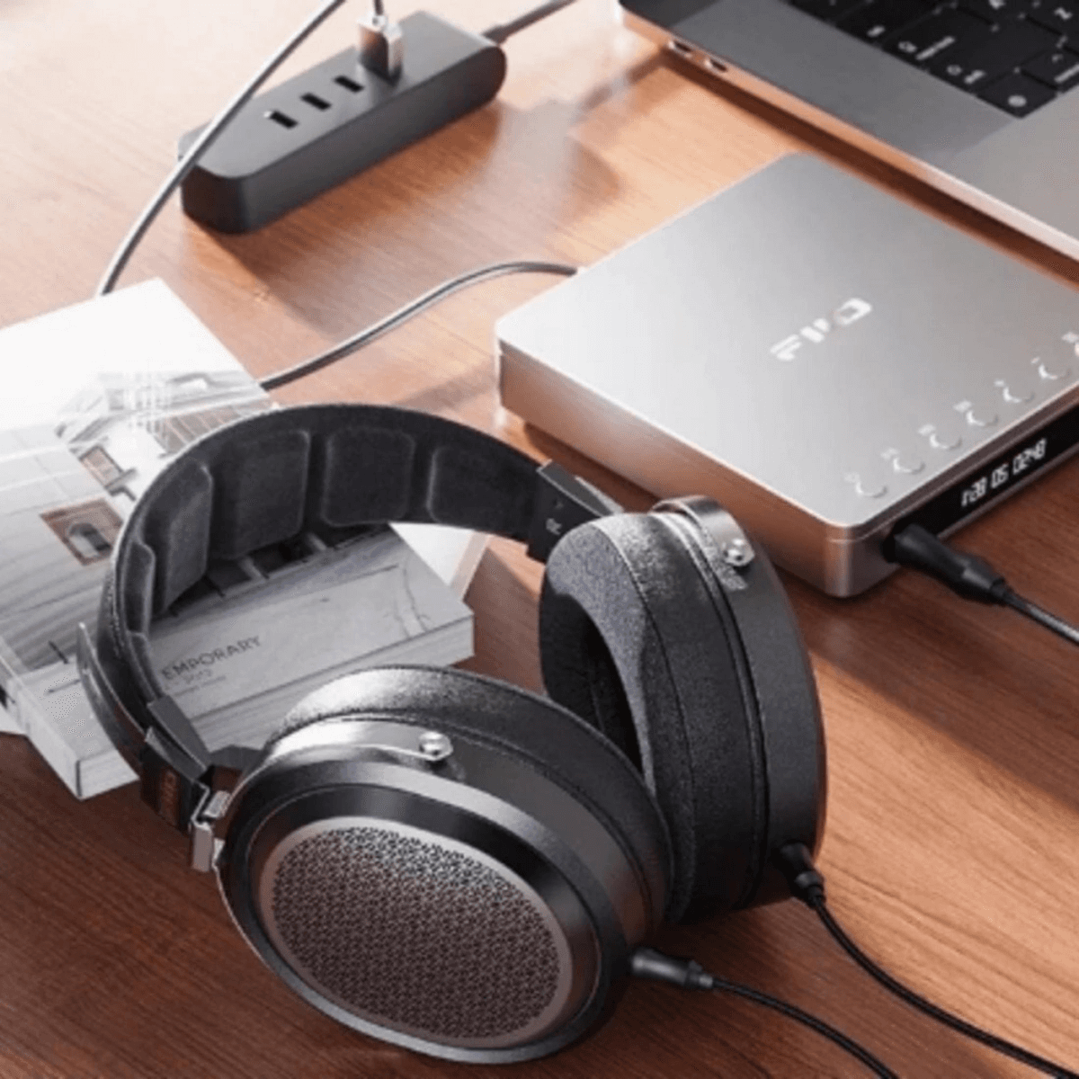 Auriculares negros sobre libros junto a un dispositivo de audio plateado y portátil en una mesa.