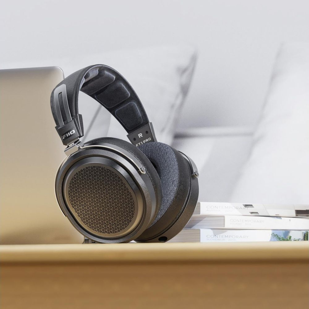 Auriculares supraaurales negros con un patrón geométrico de malla en las copas sobre una mesa de madera.