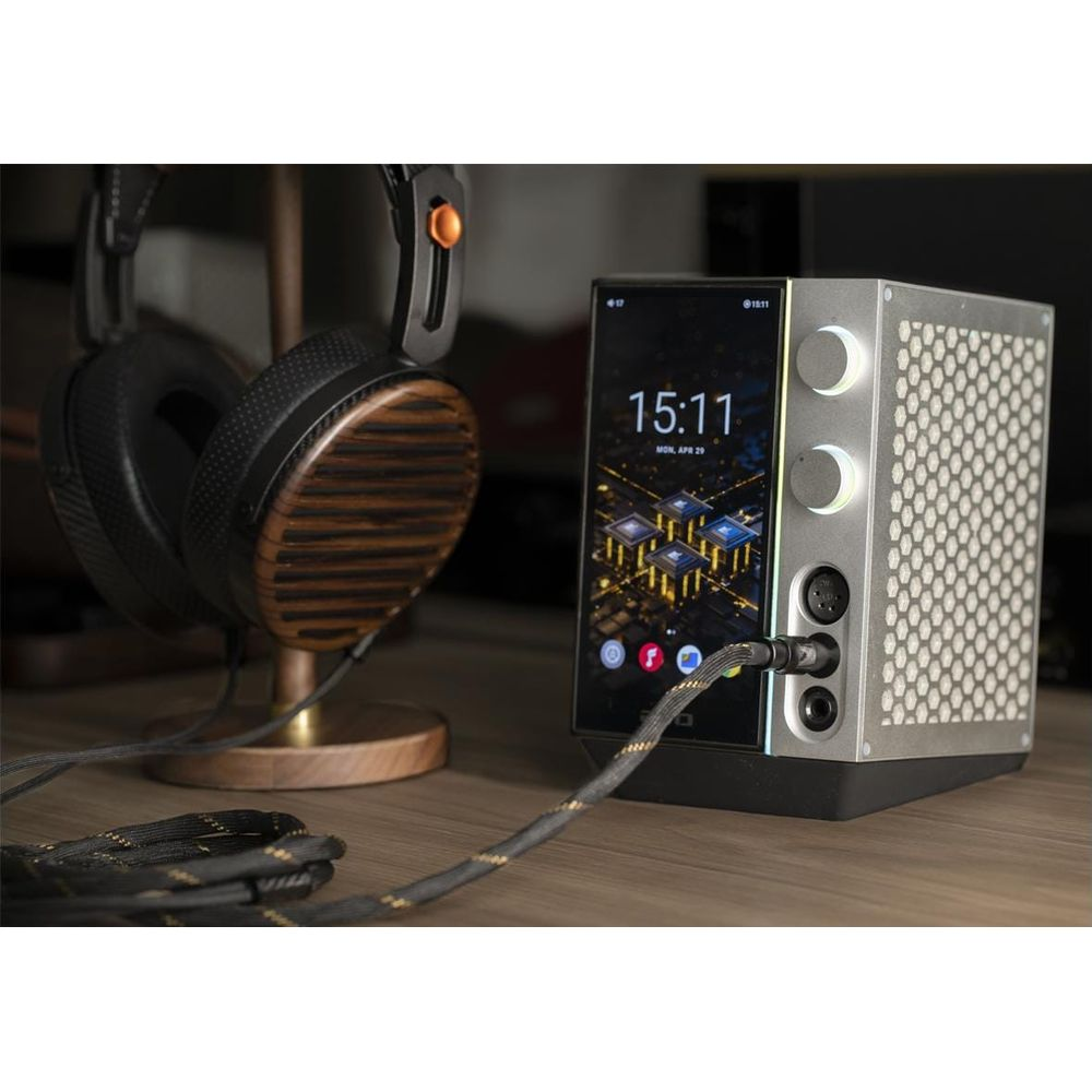 Unos auriculares de madera y un dispositivo de audio digital con pantalla y perillas sobre una mesa.