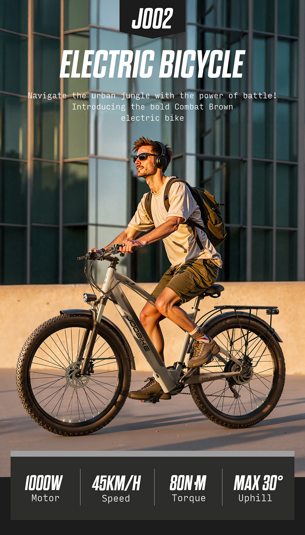 Un uomo con uno zaino guida una e-bike grigia davanti a un edificio moderno.