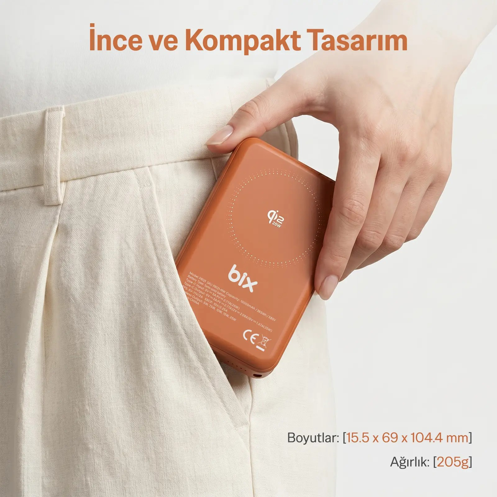 Bir el, açık renkli pantolon cebinden çıkarılan turuncu bir taşınmaz şarj cihazı tutuyor.