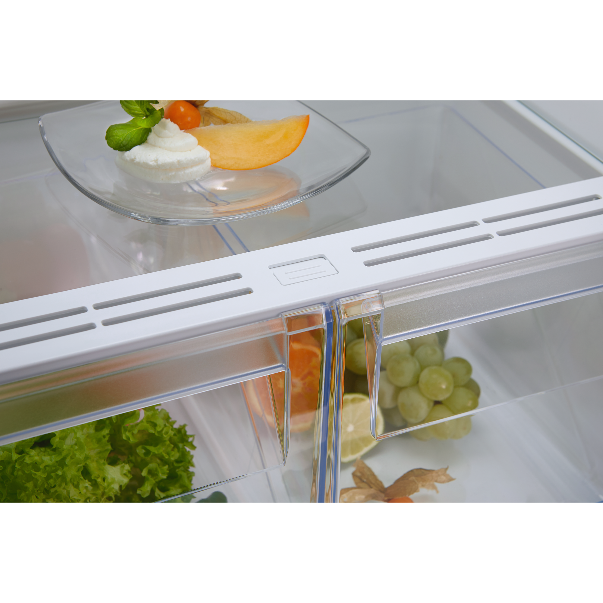 Interior de un refrigerador limpio con fruta, crema y verduras almacenadas en estantes y cajones.