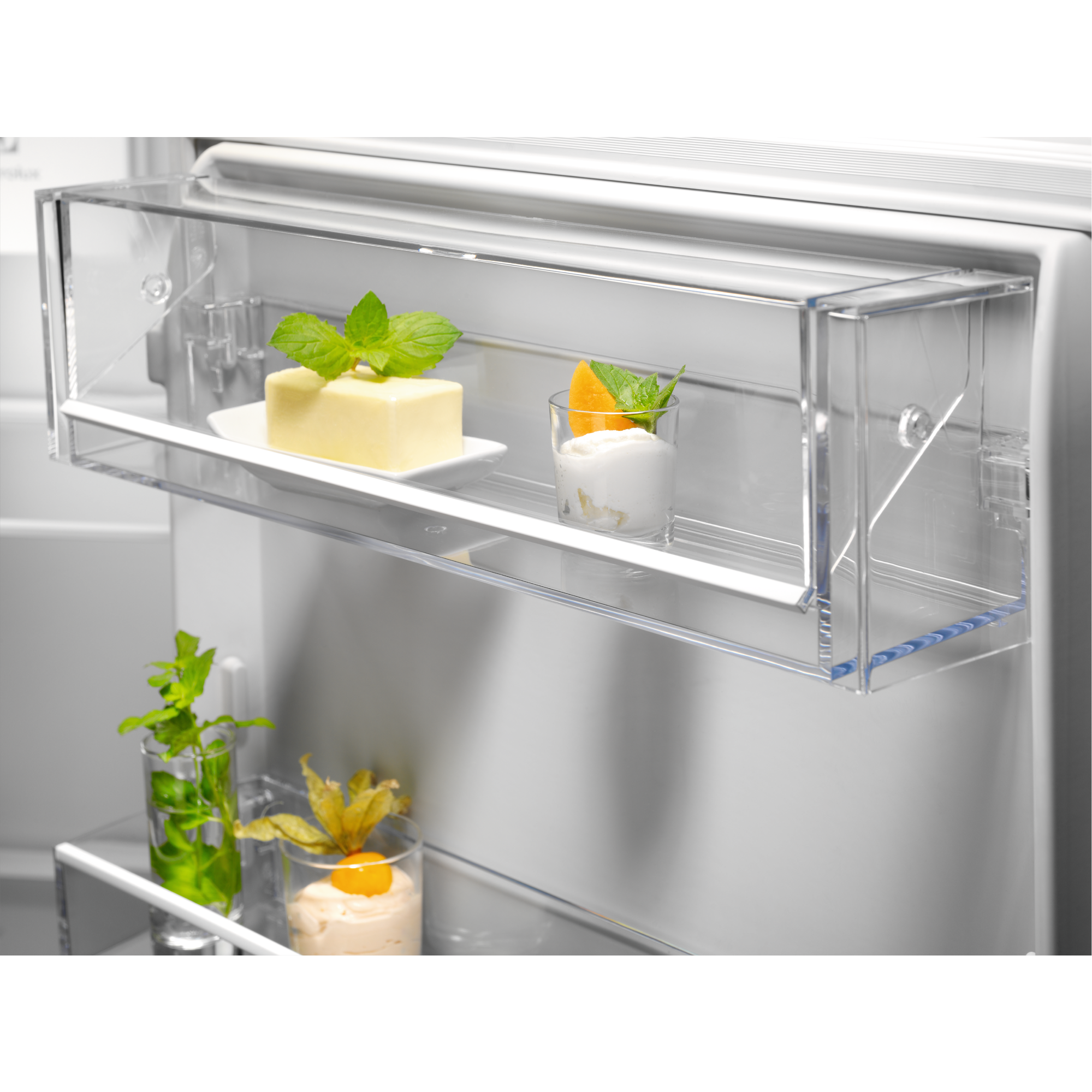 Puerta del refrigerador abierta con compartimentos transparentes, mantequilla, crema y hierbas.