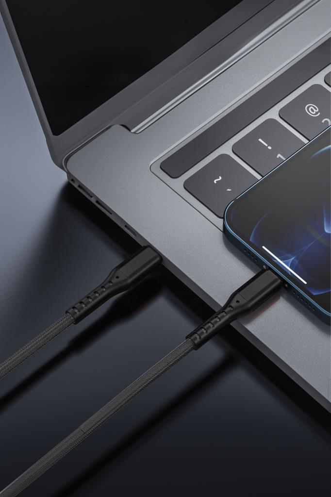 Örgülü şarj kablosu gri bir dizüstü bilgisayarı ve akıllı telefonu bağlıyor.