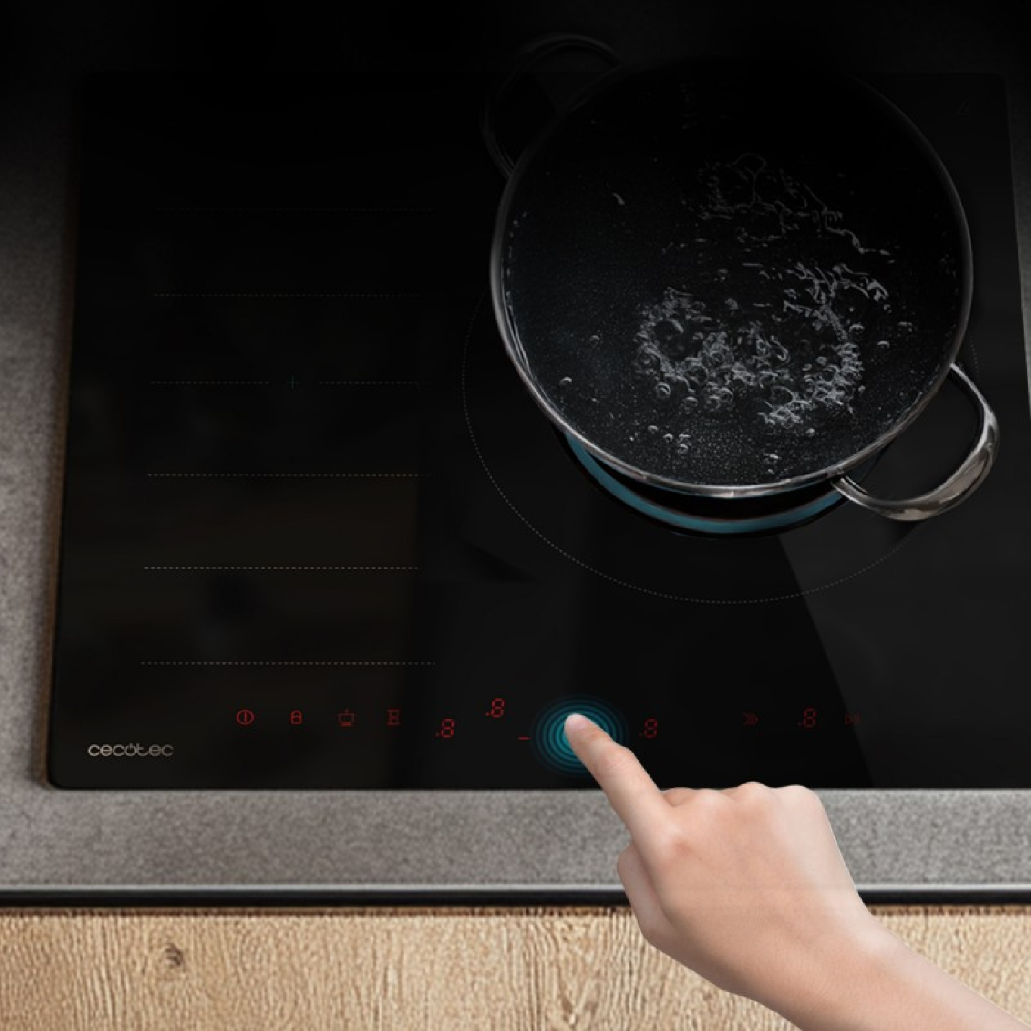 Una mano opera el panel táctil de una placa de inducción negra con una olla de agua hirviendo.