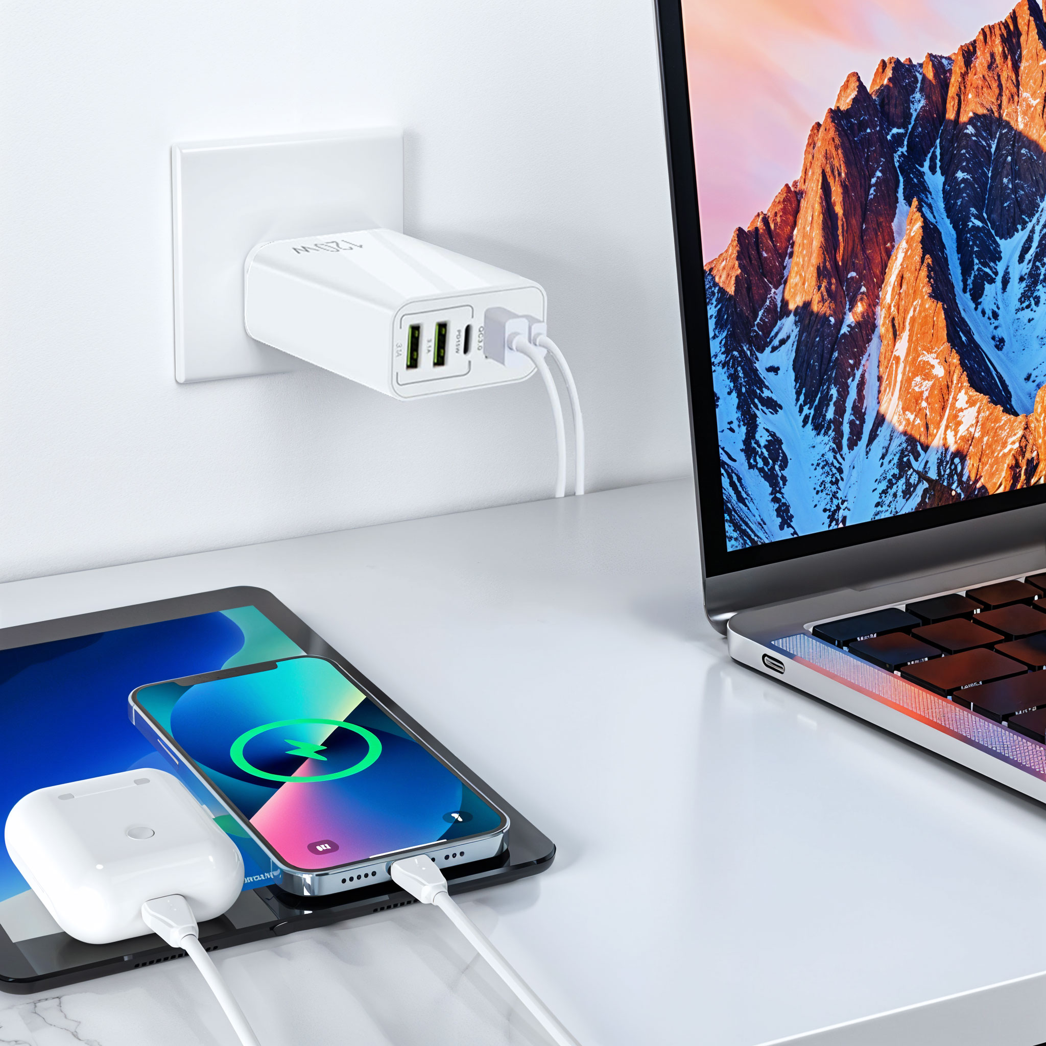 A white 120W wall charger powers a laptop, tablet, smartphone, and earbuds on a desk.