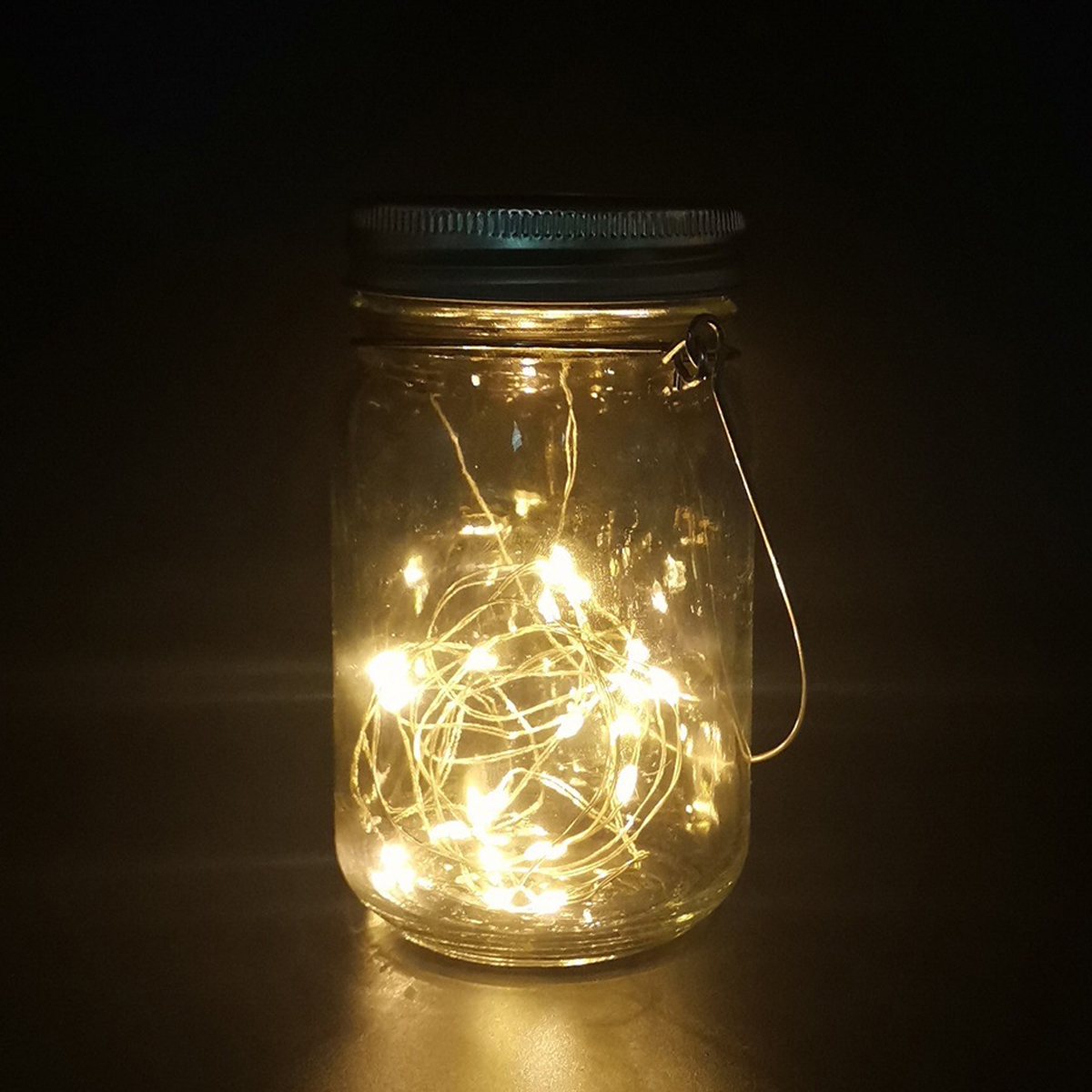 Ein beleuchtetes Einmachglas mit einer Lichterkette im Inneren auf dunklem Hintergrund.