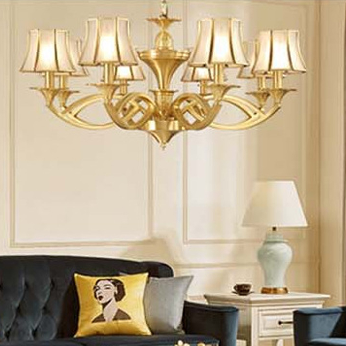 Ein eleganter Kronleuchter hängt über einem blauen Sofa mit gelbem Kissen und einer Lampe.