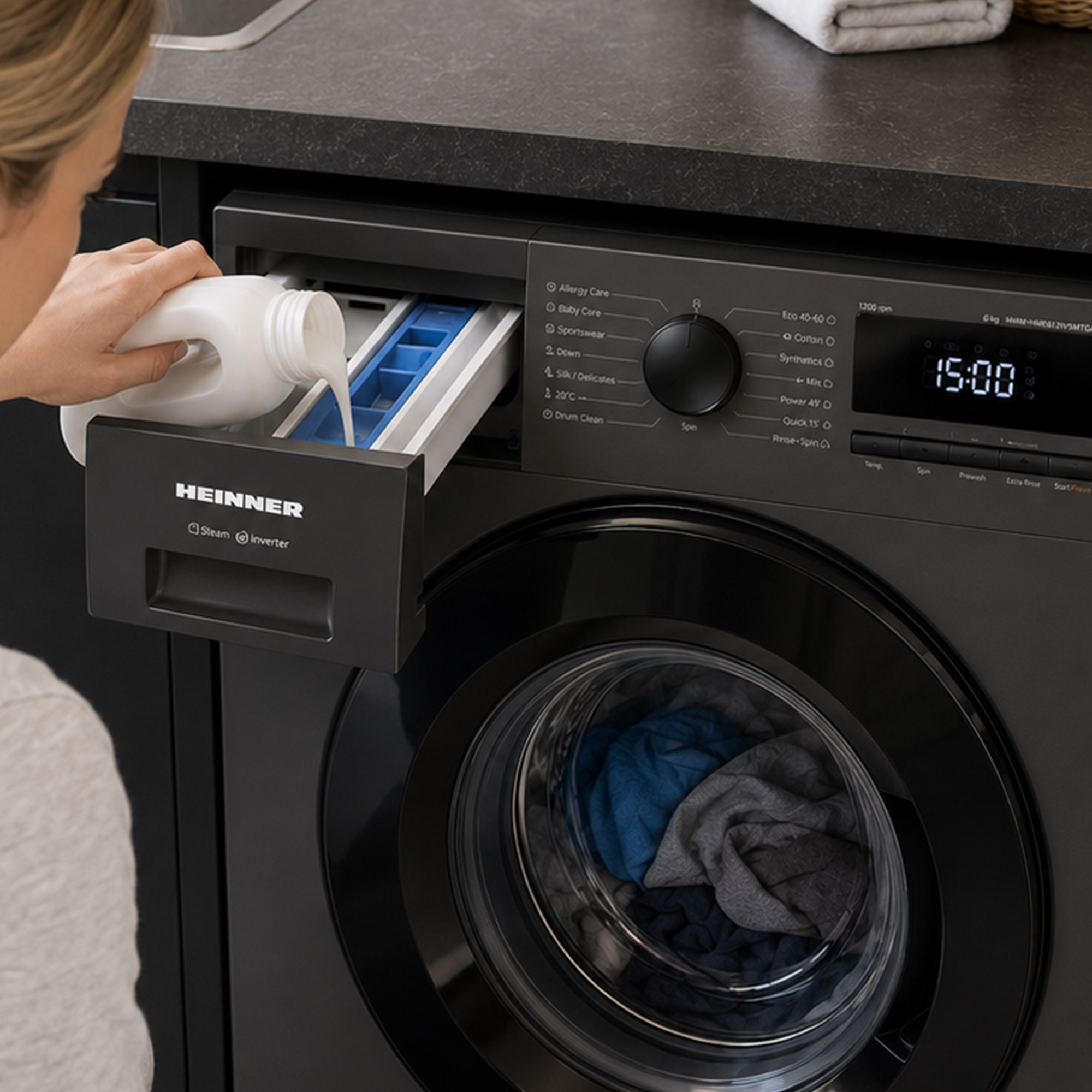 Een vrouw giet vloeibaar wasmiddel in de open lade van een donkere wasmachine met blauwe en grijze was.