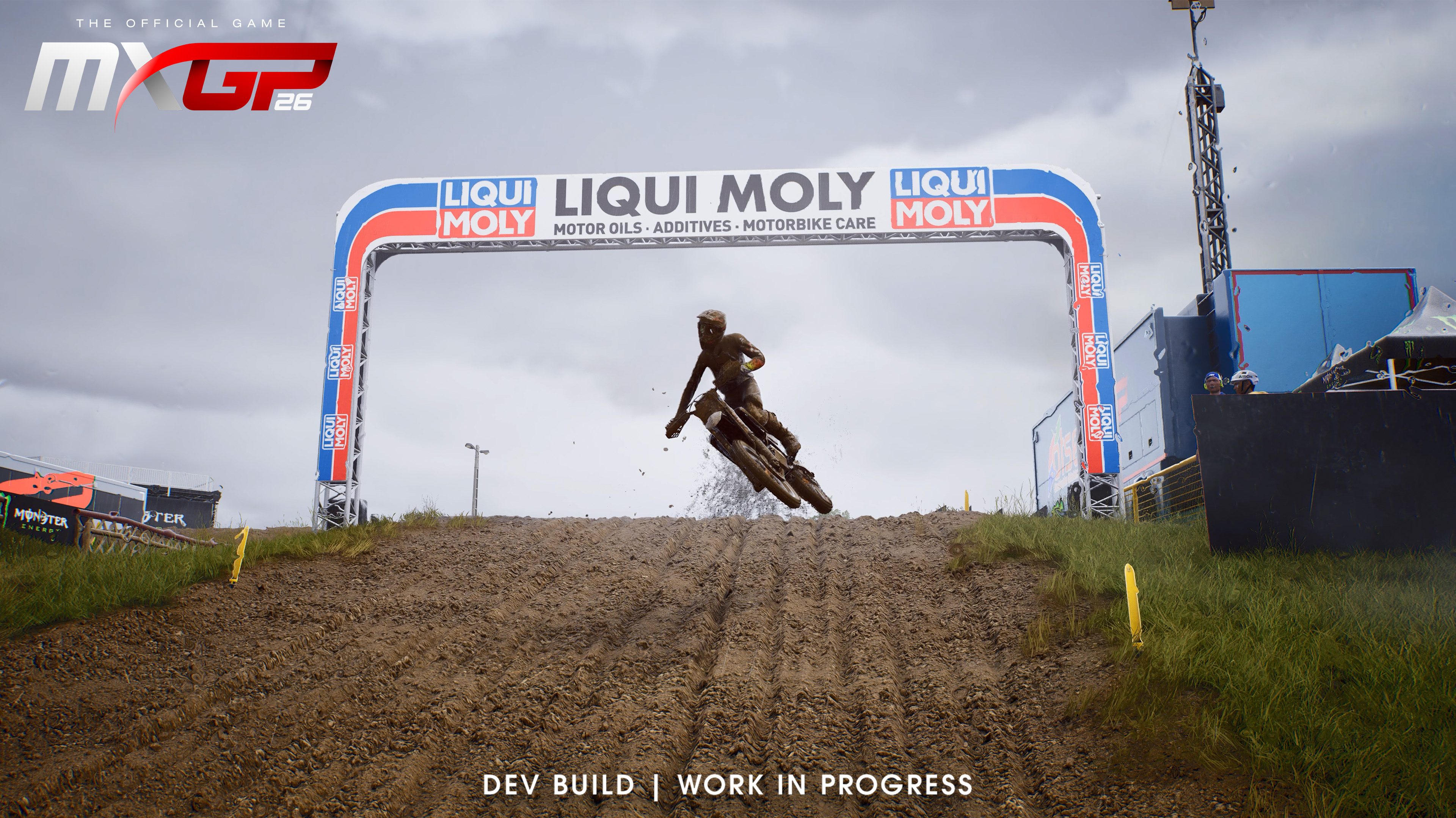 Ein Motocross-Fahrer springt mit einem Dirt-Bike über einen schlammigen Hügel unter einem Liqui Moly-Bogen.