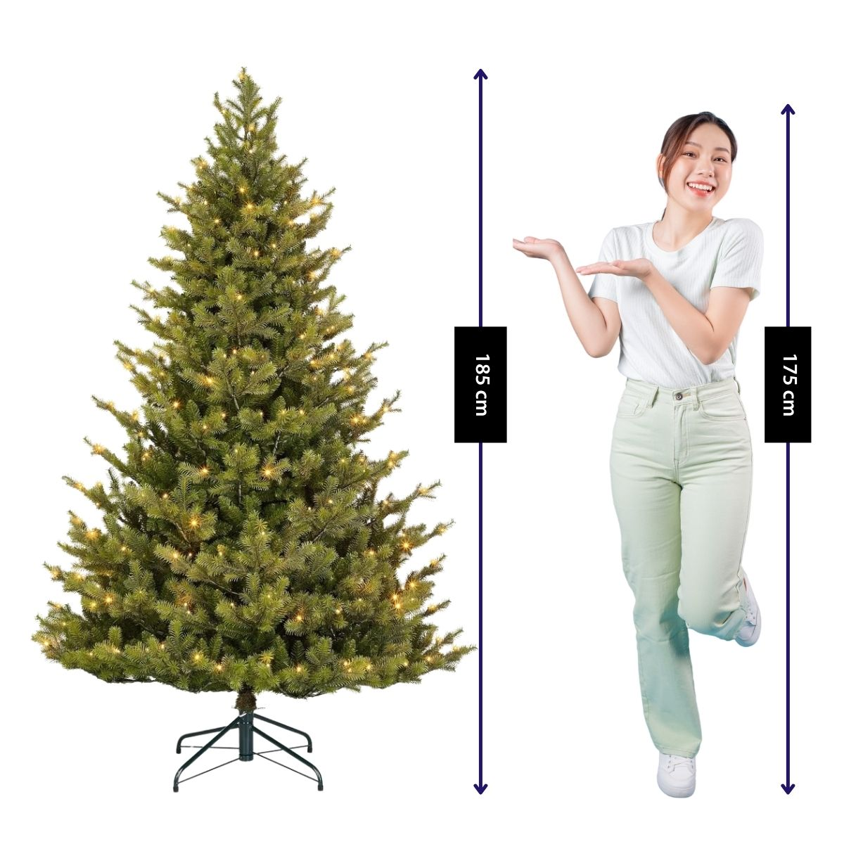 A smiling woman gestures towards a lit artificial Christmas tree with height indicators of 185 cm and 175 cm.