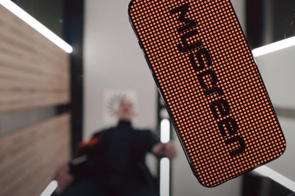 Smartfon z czerwonym wyświetlaczem LED pokazuje napis MYSCRN w nowołzesnym pokoju.
