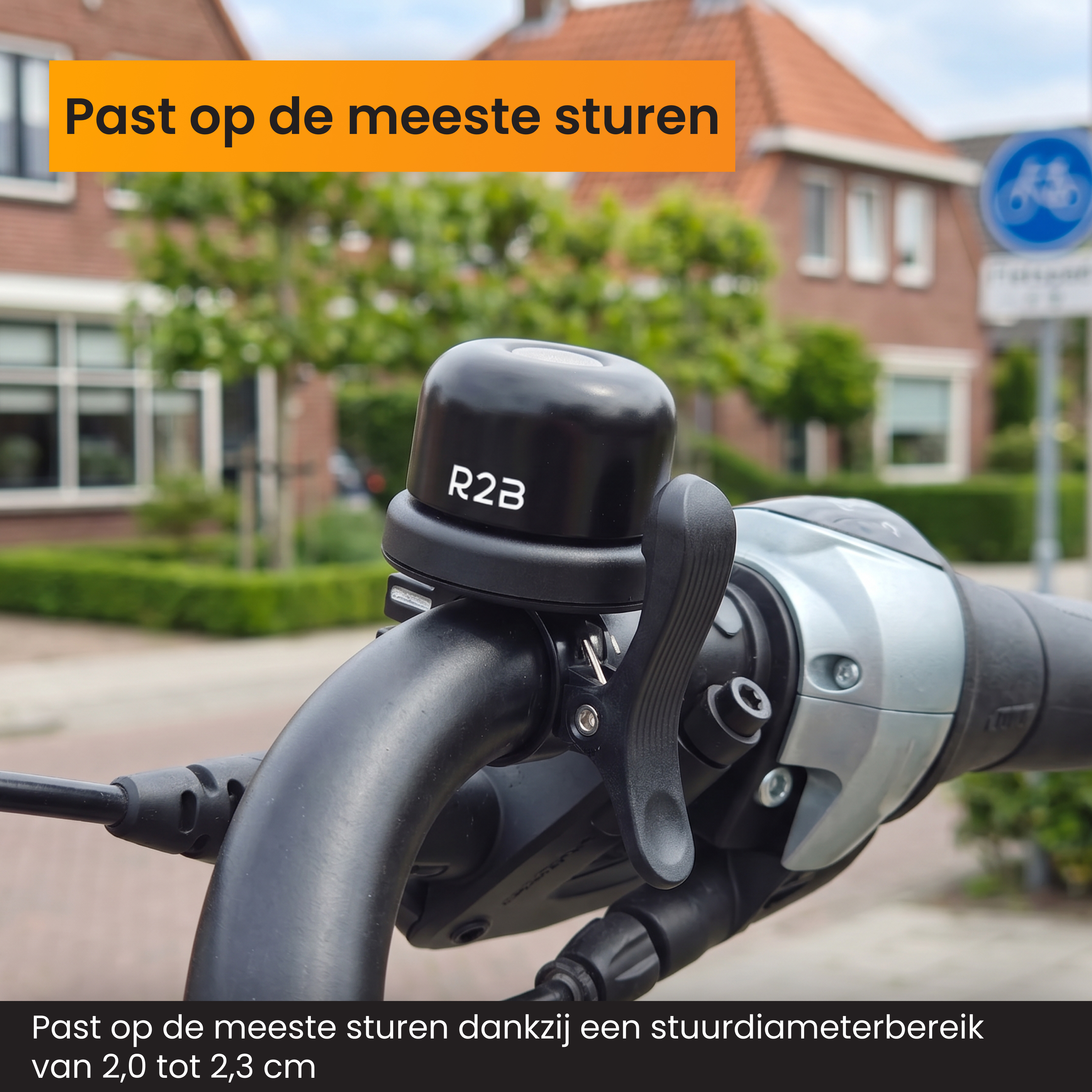 Schwarze R2B-Fahrradklingel am Lenker eines Fahrrads vor einer Straße mit Häusern.
