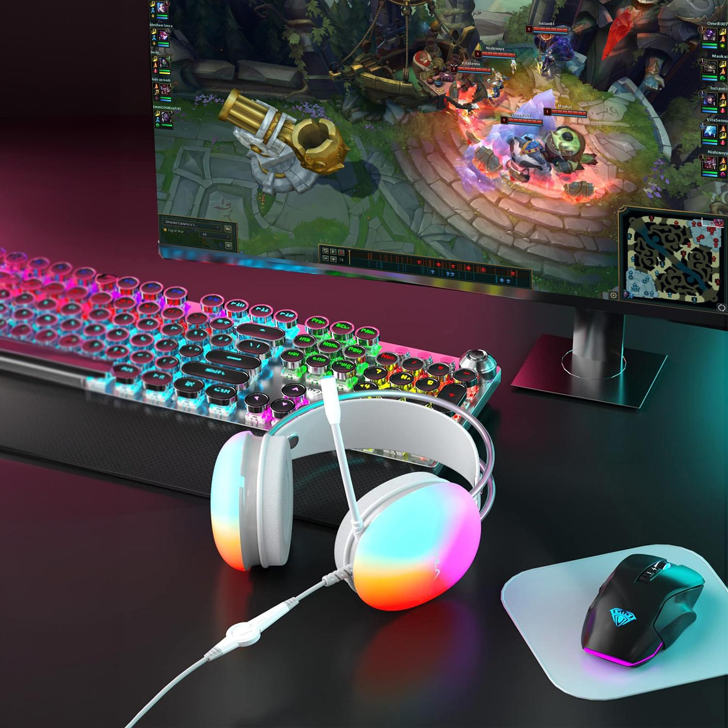 Postazione da gioco con cuffie bianche multicolore, tastiera retroilluminata, mouse e monitor con un videogioco.