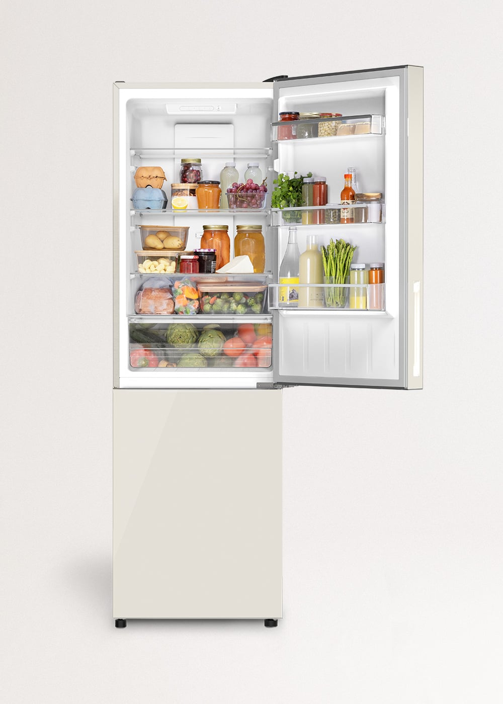 Un refrigerador abierto de color crema lleno de verduras frescas, frascos y botellas.