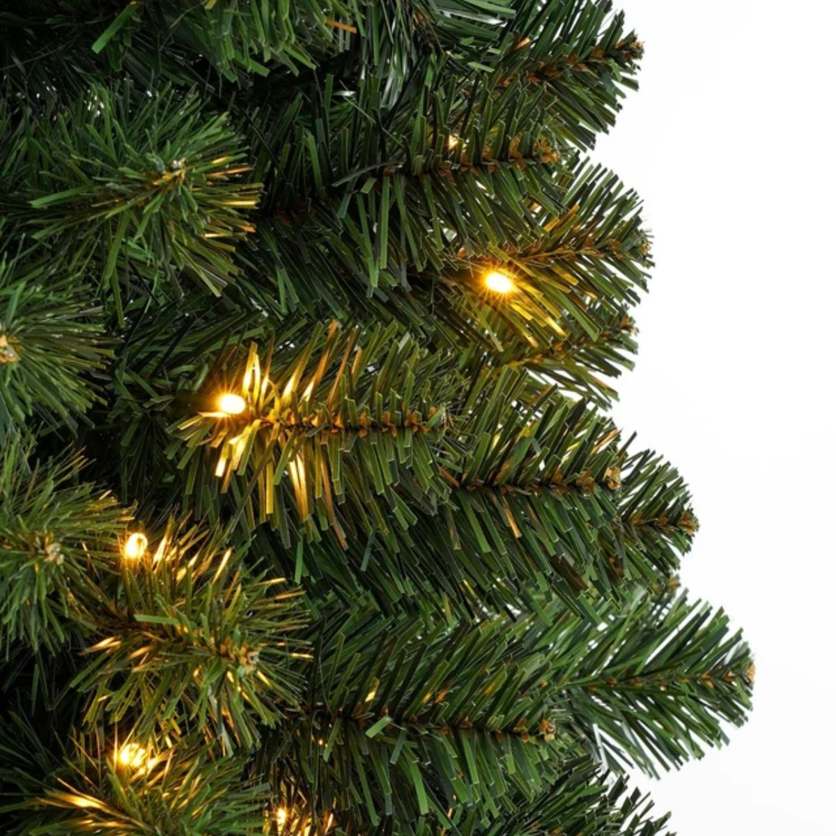 Close-up van groene takken van een kunstkerstboom met geïntegreerde warme kerstverlichting.