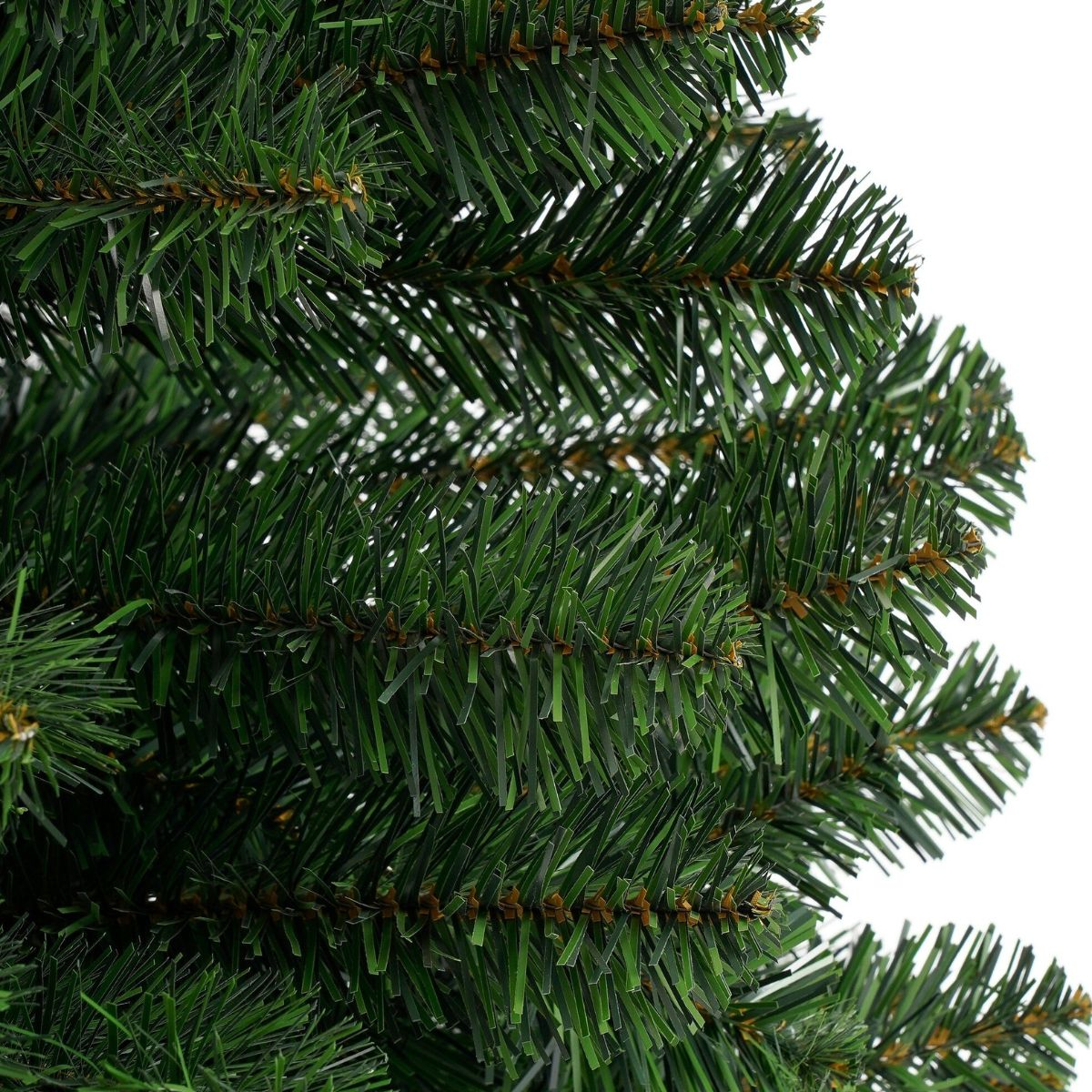 Close-up van groene kunstkerstboomtakken tegen een witte achtergrond.
