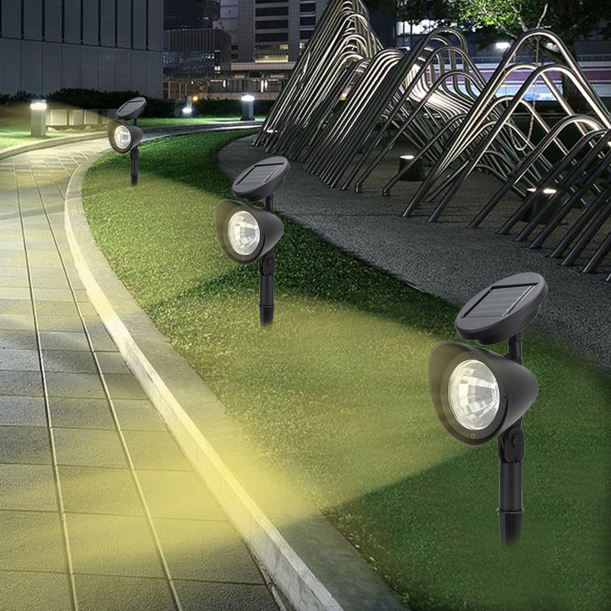 Drei schwarze Solar-Gartenleuchten beleuchten nachts einen gepflasterten Weg neben einer Grünfläche und einer Metallskulptur.