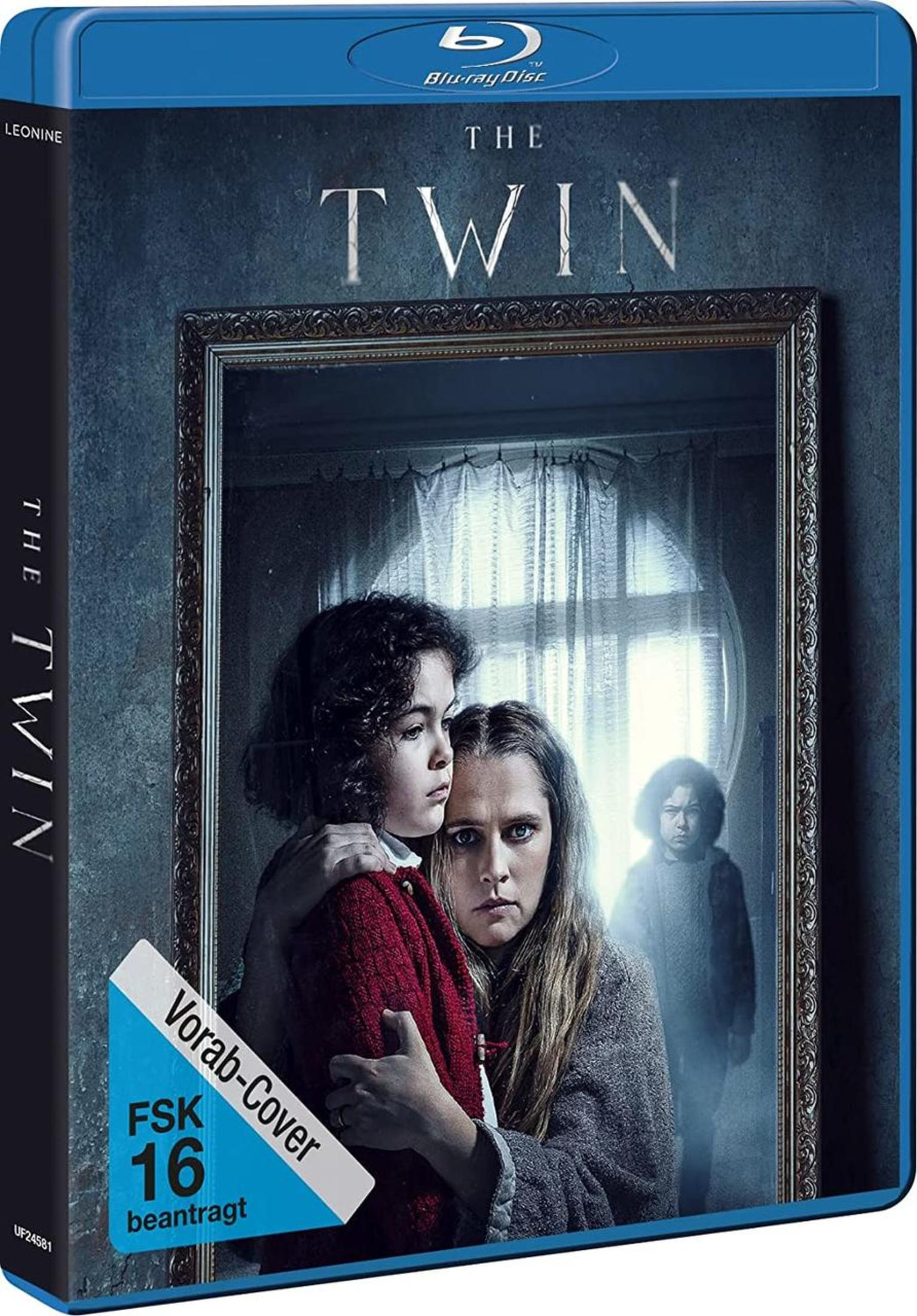 Blu-ray-Cover von Der Zwilling mit einer besorgten Mutter, einem Kind und einer zweiten Gestalt im Hintergrund.