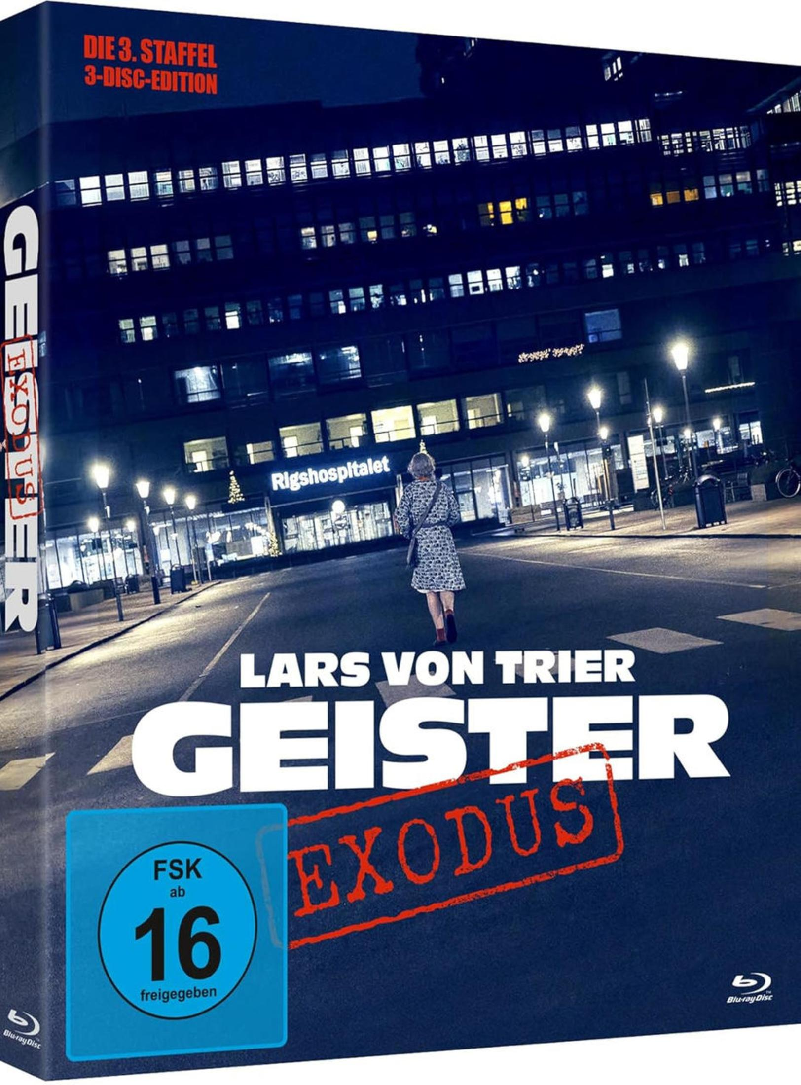 Eine Frau geht nachts auf eine große, beleuchtete Krankenhausfassade zu.