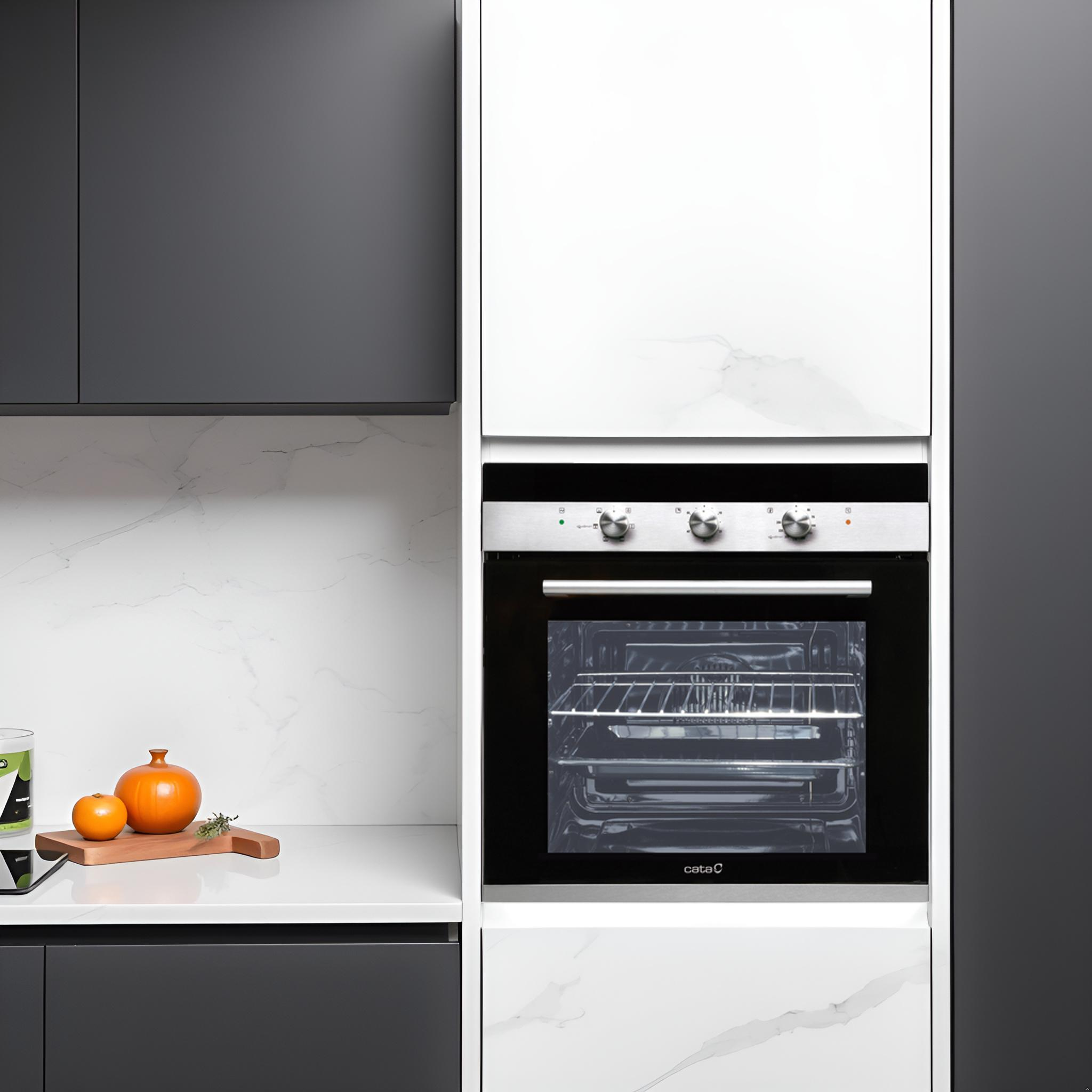 Cocina moderna con horno empotrado, gabinetes grises y encimera de mármol blanco con un pequeño cuenco naranja.