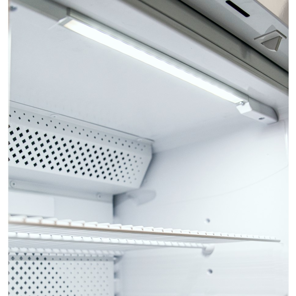 Interno di un frigorifero bianco con striscia LED superiore e ripiani.