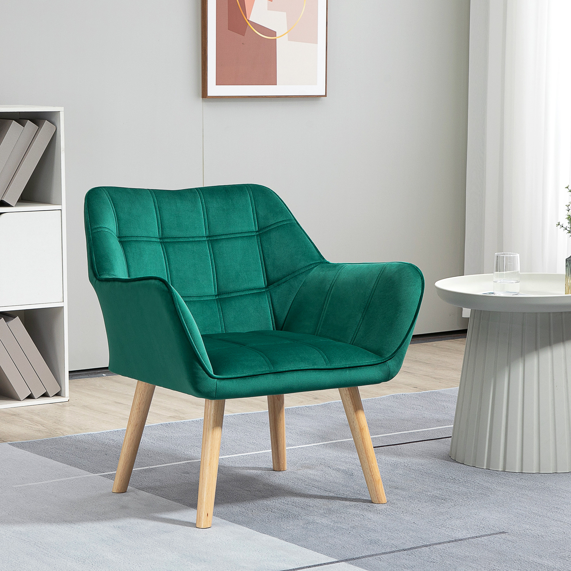 Una poltrona in velluto verde con gambe in legno su un tappeto in una stanza moderna con tavolo bianco e mensola.
