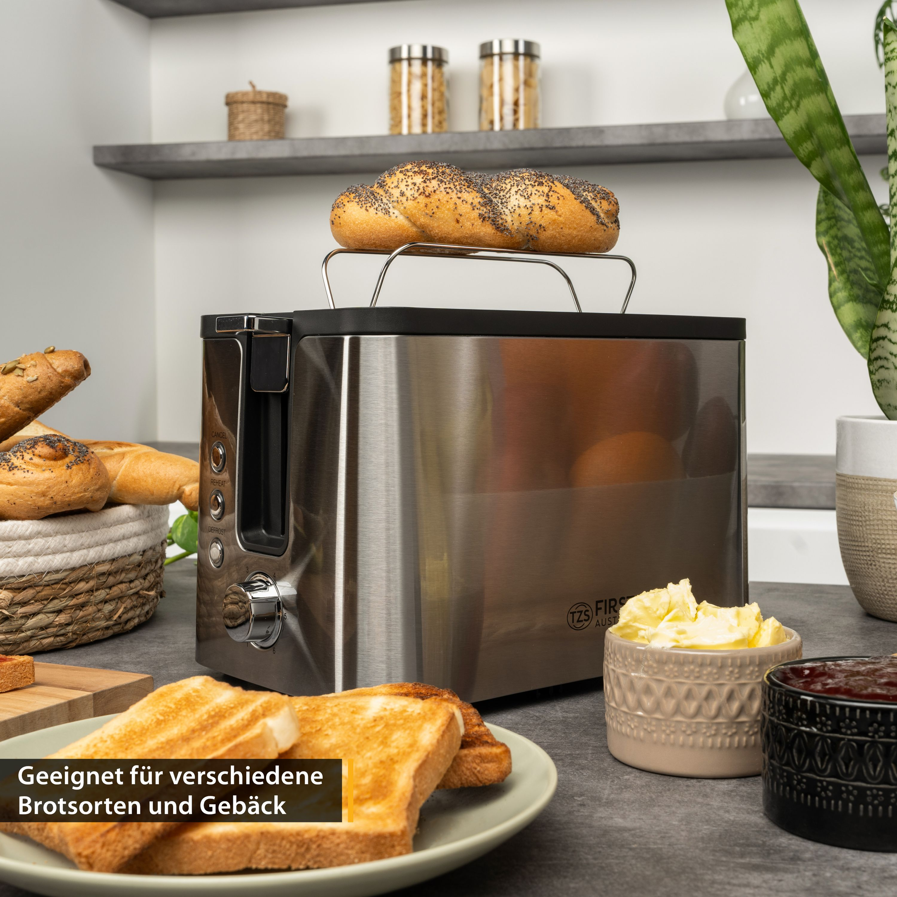 Edelstahl-Toaster auf einer Küchentheke mit Toastbrot, Butter, Marmelade und Gebäck.