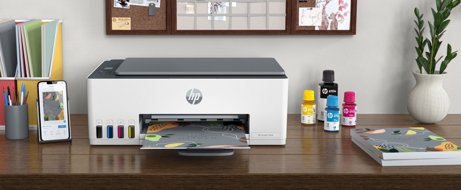 Una stampante bianca HP Smart Tank è su una scrivania di legno, circondata da flaconi di inchiostro e documenti.