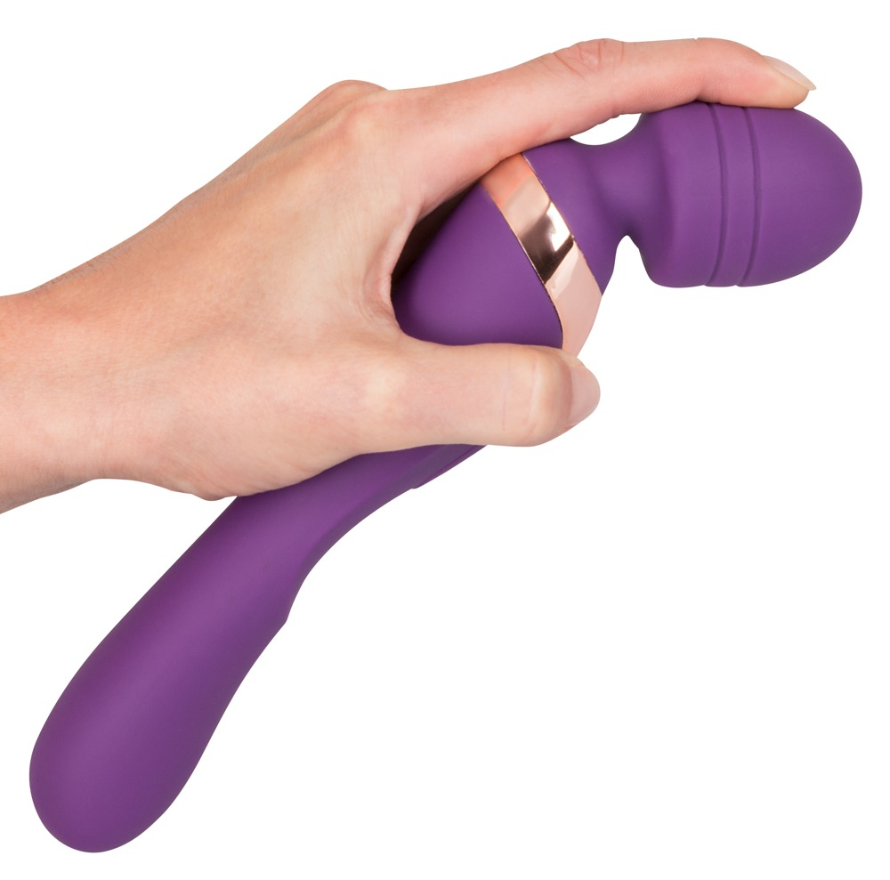 Eine Hand hält einen violetten Vibrator mit roségoldenem Ring vor weißem Hintergrund.