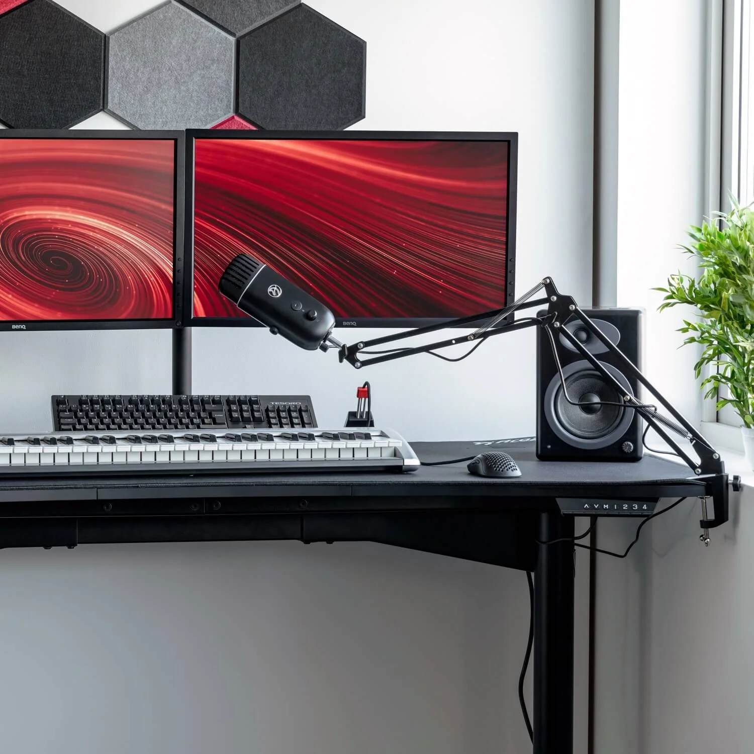 Un escritorio con dos monitores con gráficos rojos, un micrófono, altavoces, un teclado y un teclado musical.