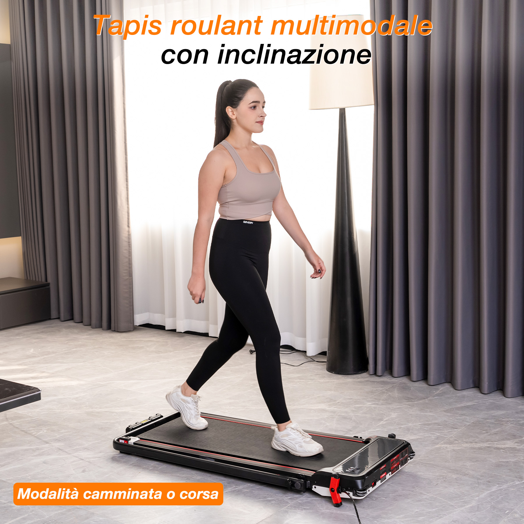 Una donna in abbigliamento sportivo cammina su un tapis roulant piatto in una stanza con tende scure.