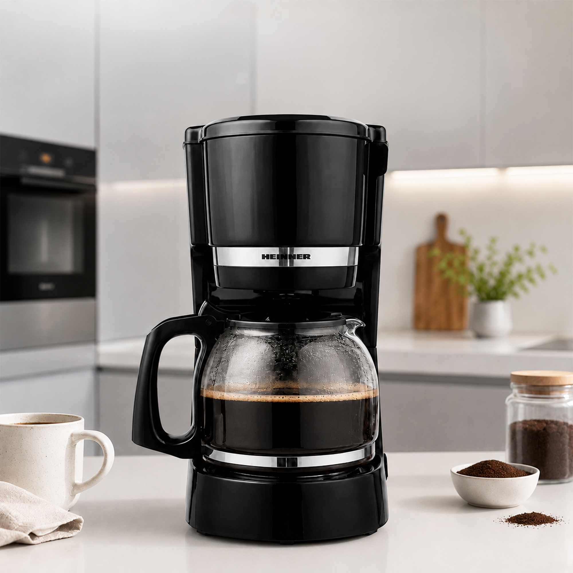 A black coffee maker on a white kitchen counter with a glass carafe filled with brewed coffee.