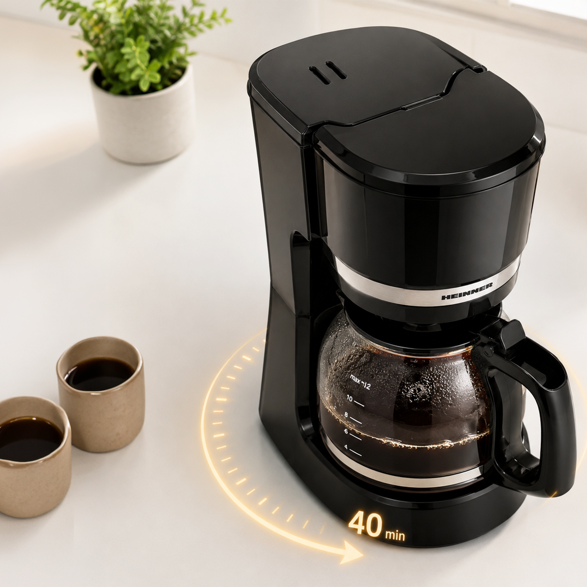 A black coffee maker with a glass carafe on a white counter, with two cups of coffee and a small potted plant.