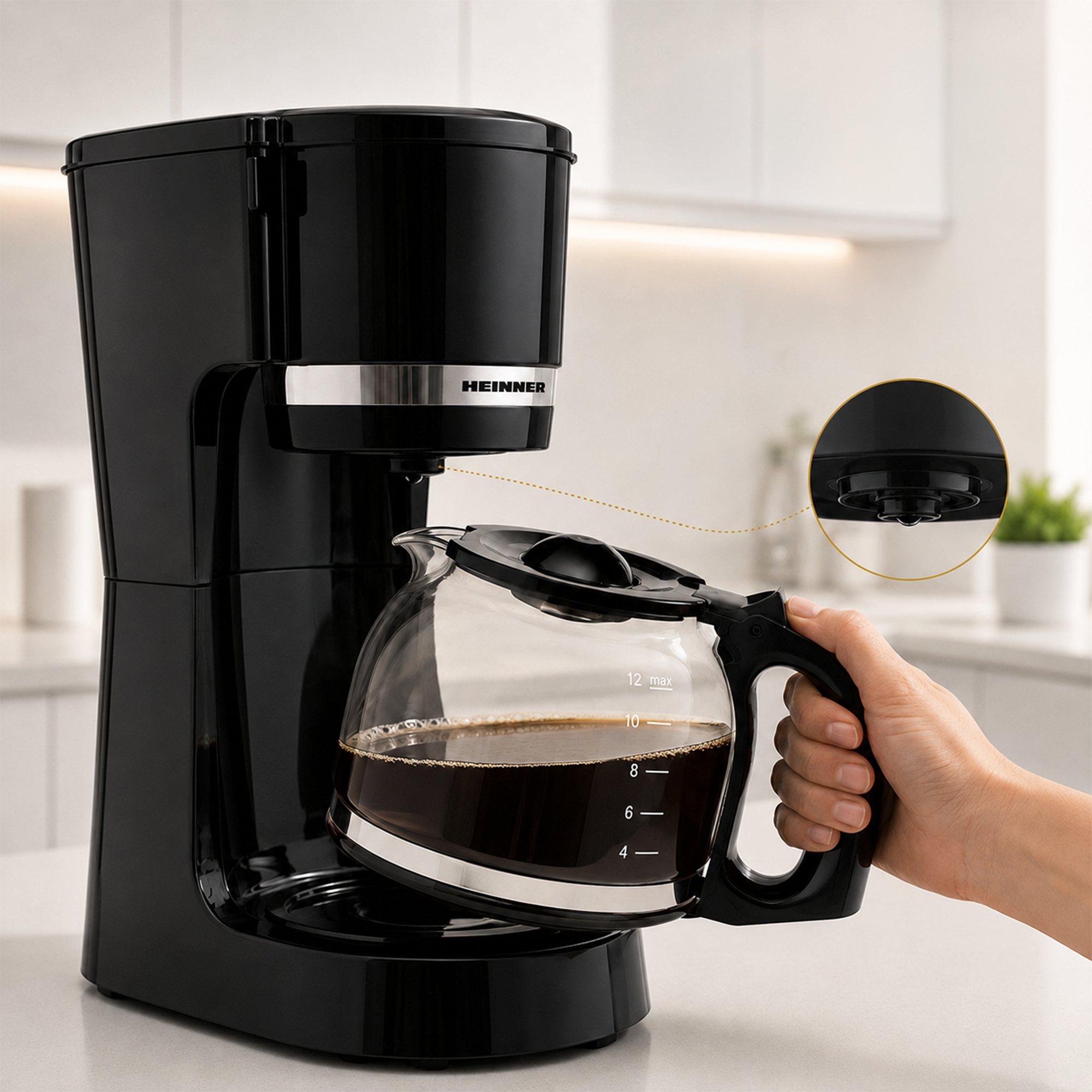 A black coffee maker on a counter with a hand removing a filled glass pot, an inset circle shows the bottom detail.