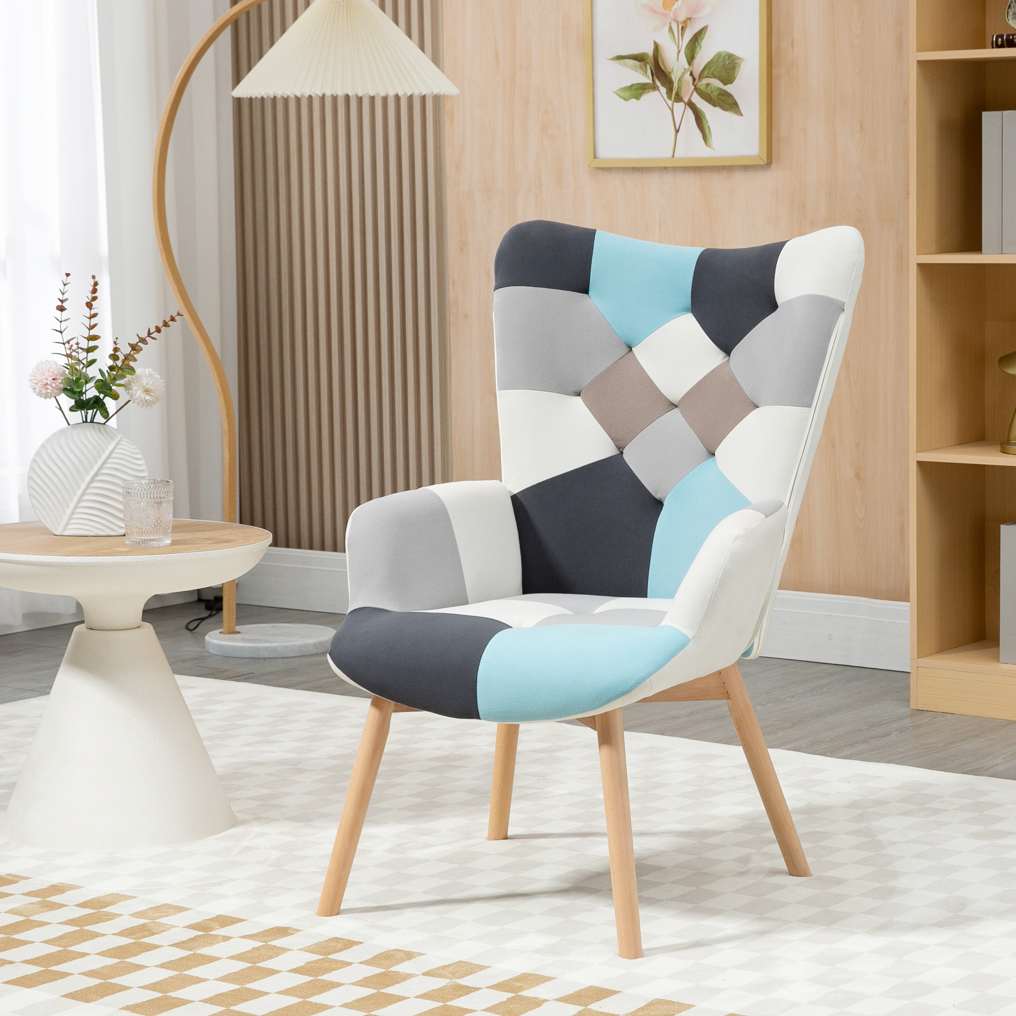 Una poltrona imbottita patchwork con motivi blu, grigi e bianchi si trova su un tappeto in una stanza luminosa.