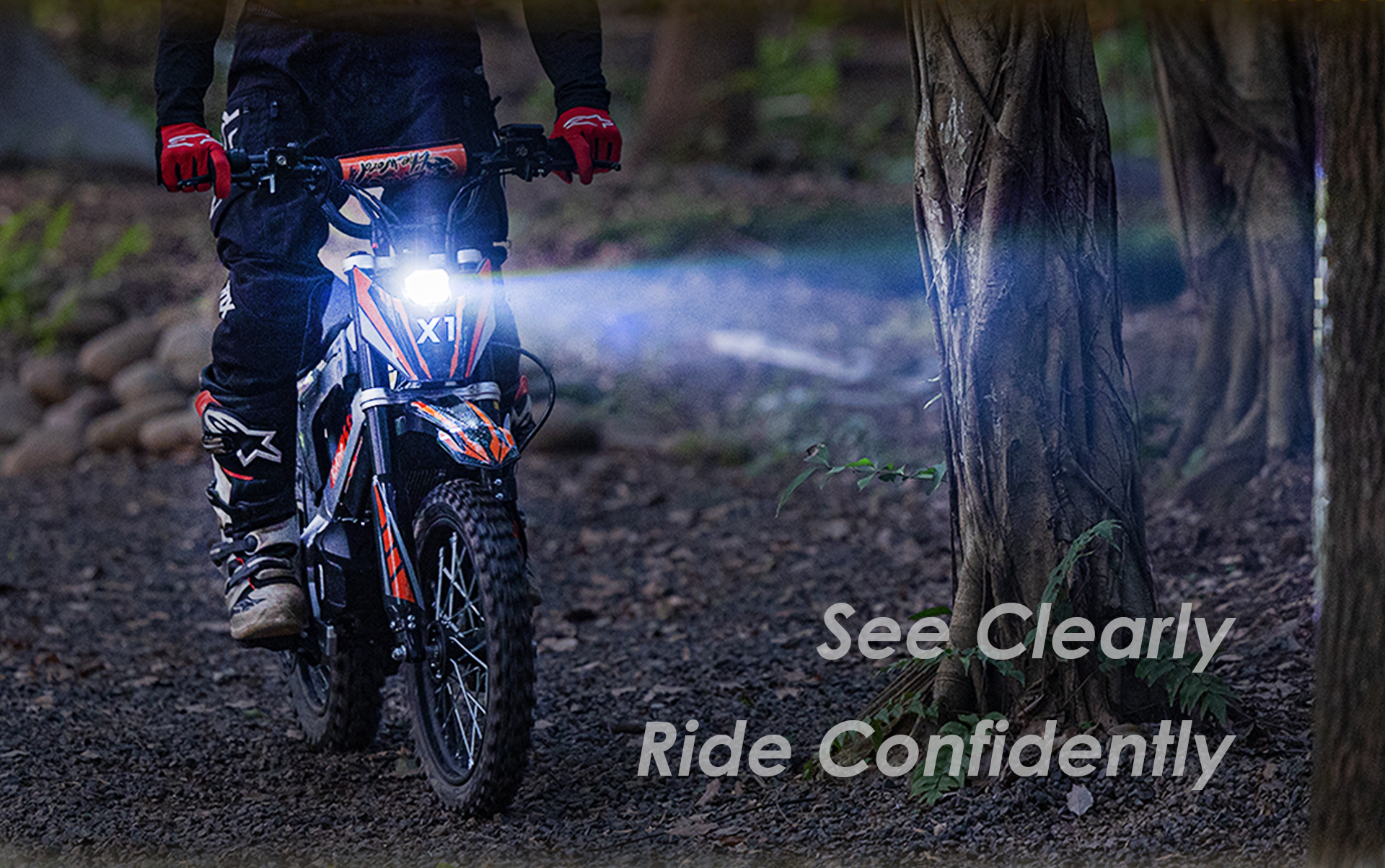 Un motociclista en una moto de cross con un faro brillante conduce por una zona boscosa al atardecer.