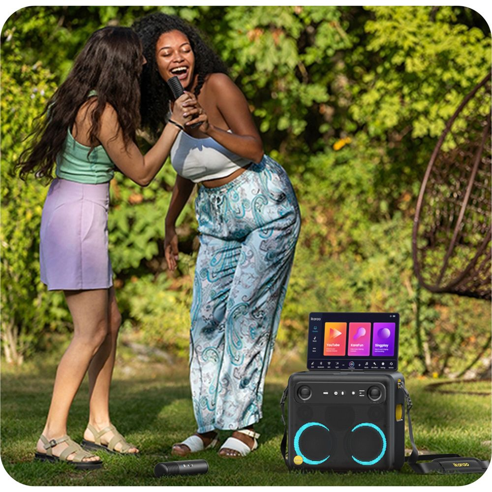 Zwei junge Frauen singen im Garten in Mikrofone neben einer Karaoke-Anlage.