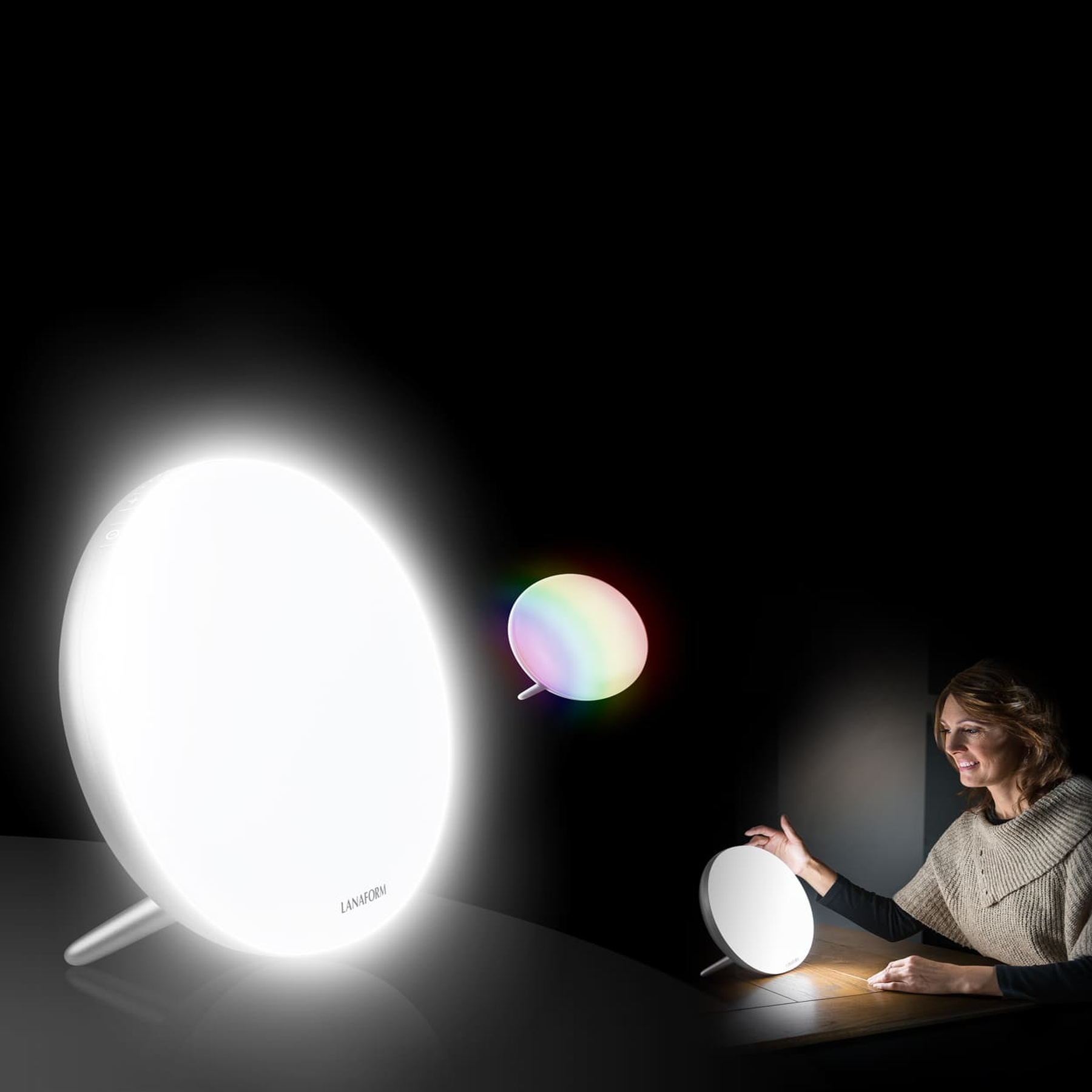 Eine Frau sitzt an einem Tisch und berührt eine helle, runde Lanaform-Tageslichtlampe in einem dunklen Raum.